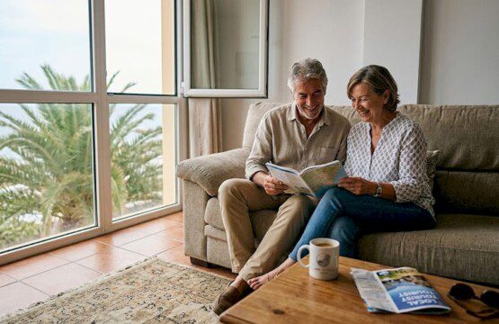 Ein Paar sitzt in seiner Ferienwohnung auf Teneriffa und schmiedet Pläne für den Urlaub.