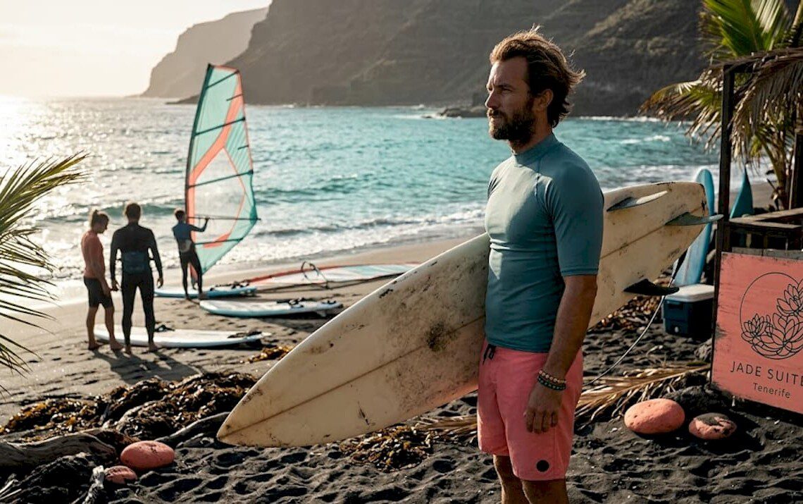 Ein Surflehrer begutachtet am Strand von Teneriffa die Wellen, bevor der Unterricht beginnt.