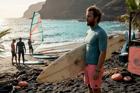 Ein Surflehrer begutachtet am Strand von Teneriffa die Wellen, bevor der Unterricht beginnt.