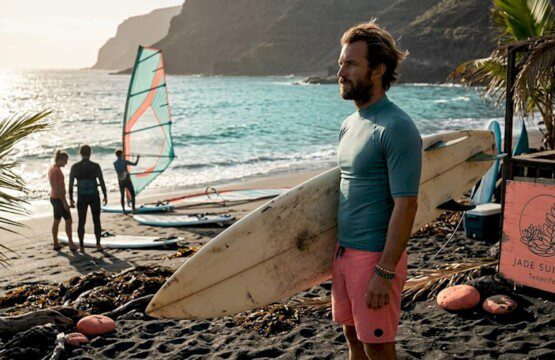 Ein Surflehrer begutachtet am Strand von Teneriffa die Wellen, bevor der Unterricht beginnt.
